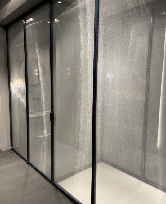 Cabine de douche toute hauteur, collection suite chez Vismaravetro. Paroi en verre securiplus reeded et profilés en aluminium noir.