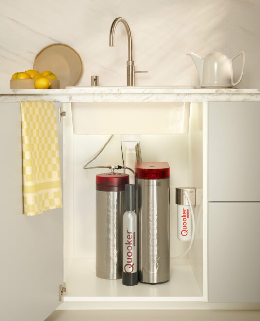 Installation sous évier du réservoir Quooker PRO3 et du module CUBE. Ce système compact permet d'avoir eau bouillante, fraîche, plate et pétillante sans encombrer le plan de travail. À découvrir chez Hydropolis
